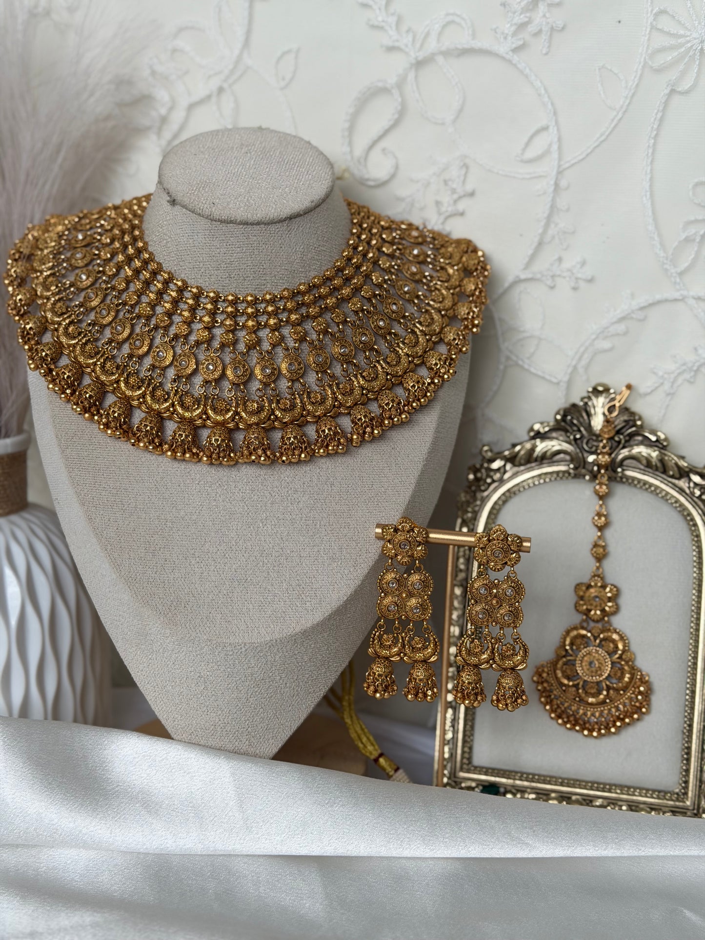 Gold necklace and earrings on a mannequin bust with a white textured background